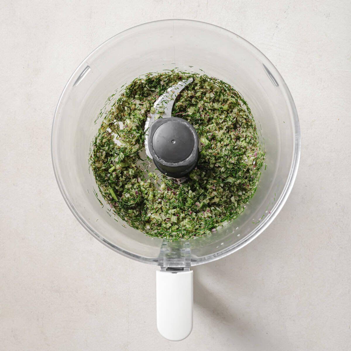 onion, celery, dill, and capers in a food processor after being pulsed.