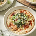 Side angle of bowl of savory oatmeal with Chinese chili crisp and sautéed greens.