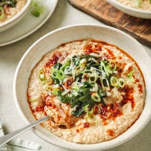 Side angle of bowl of savory oatmeal with Chinese chili crisp and sautéed greens.
