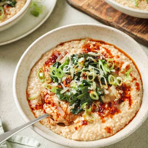 Side angle of bowl of savory oatmeal with Chinese chili crisp and sautéed greens.