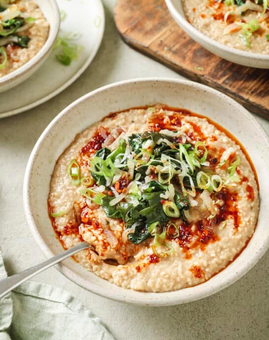 Side angle of bowl of savory oatmeal with Chinese chili crisp and sautéed greens.