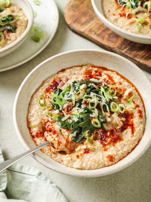 Side angle of bowl of savory oatmeal with Chinese chili crisp and sautéed greens.