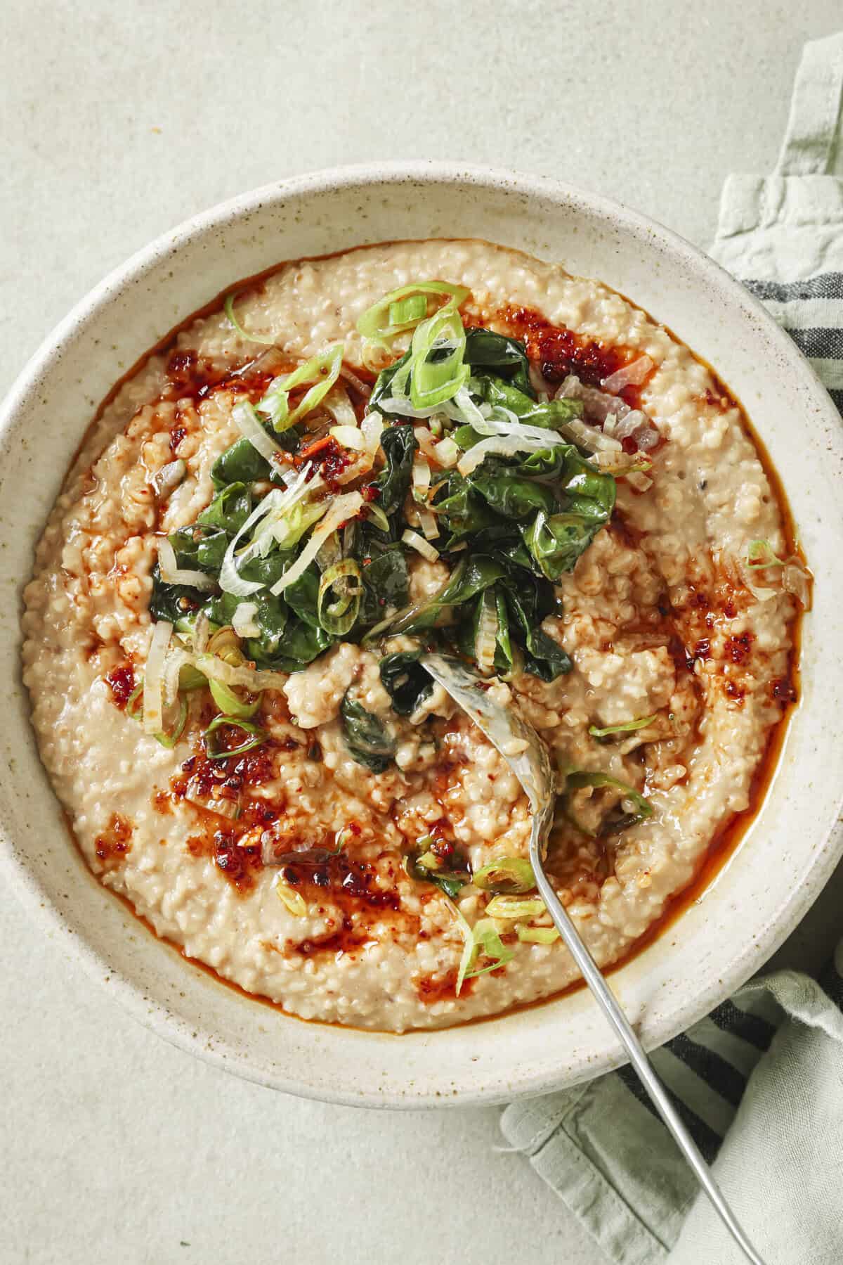 close up of savory oatmeal topped with swiss chard, scallions and chili crisp.