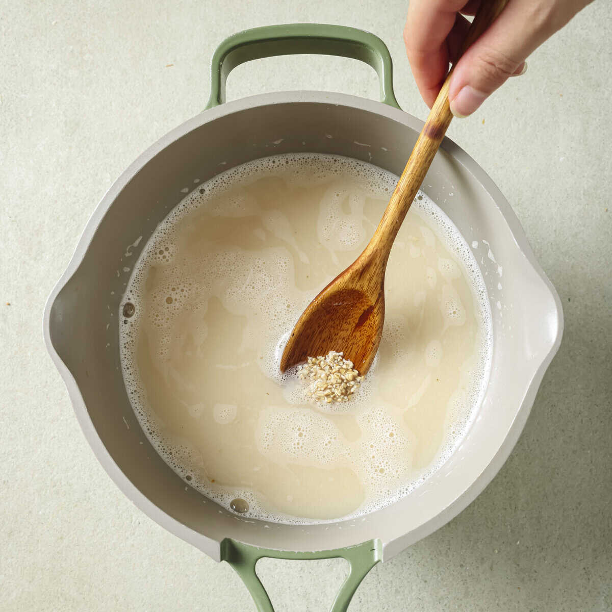 person stirring oats and water while they're cooking in the pot.