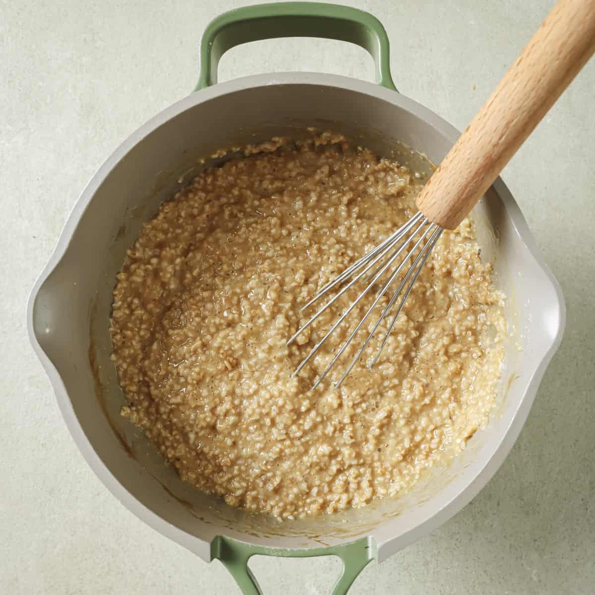 nutritional yeast and soy sauce stirred into oats in pot with a whisk in it.