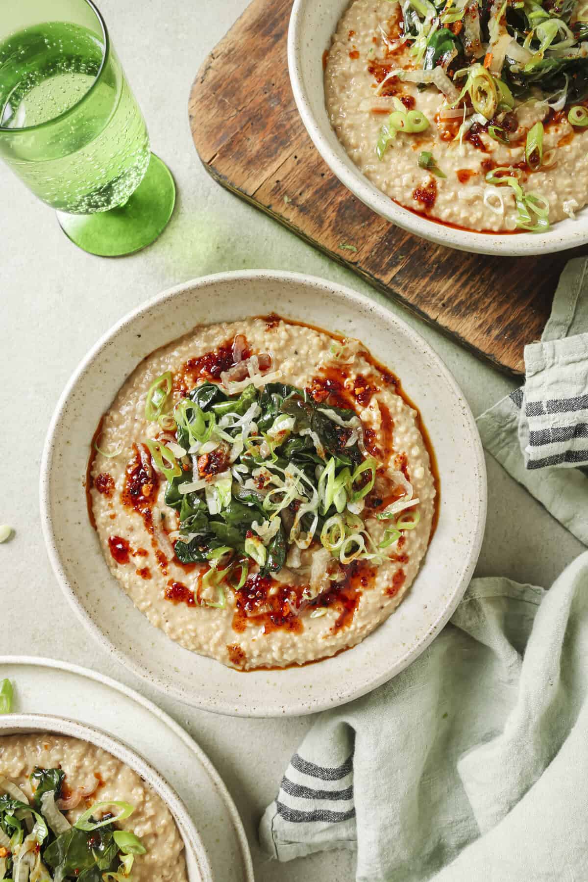 Overhead view of three bowls of savory oatmeal on a table.
