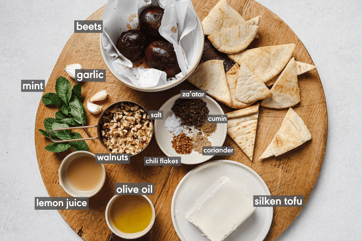 ingredients for beet dip in small bowls on a wooden cutting board.