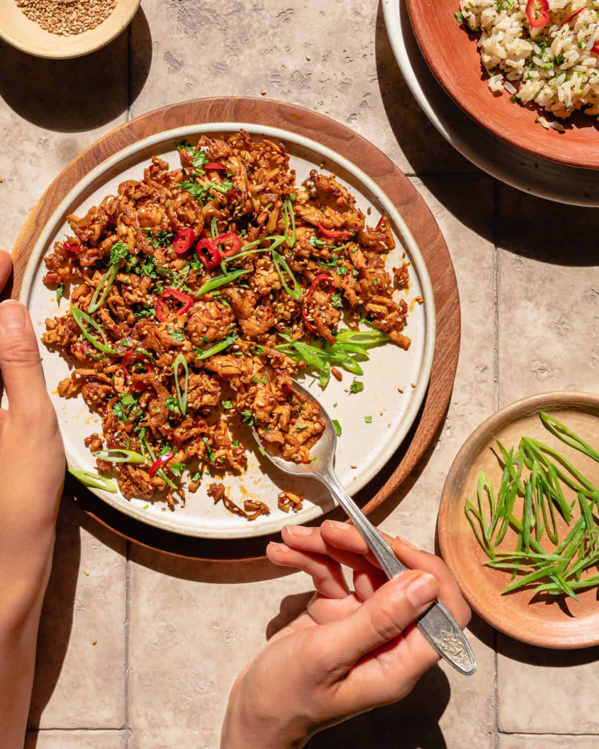 person taking a spoonful of super savory grated tofu from a plate.