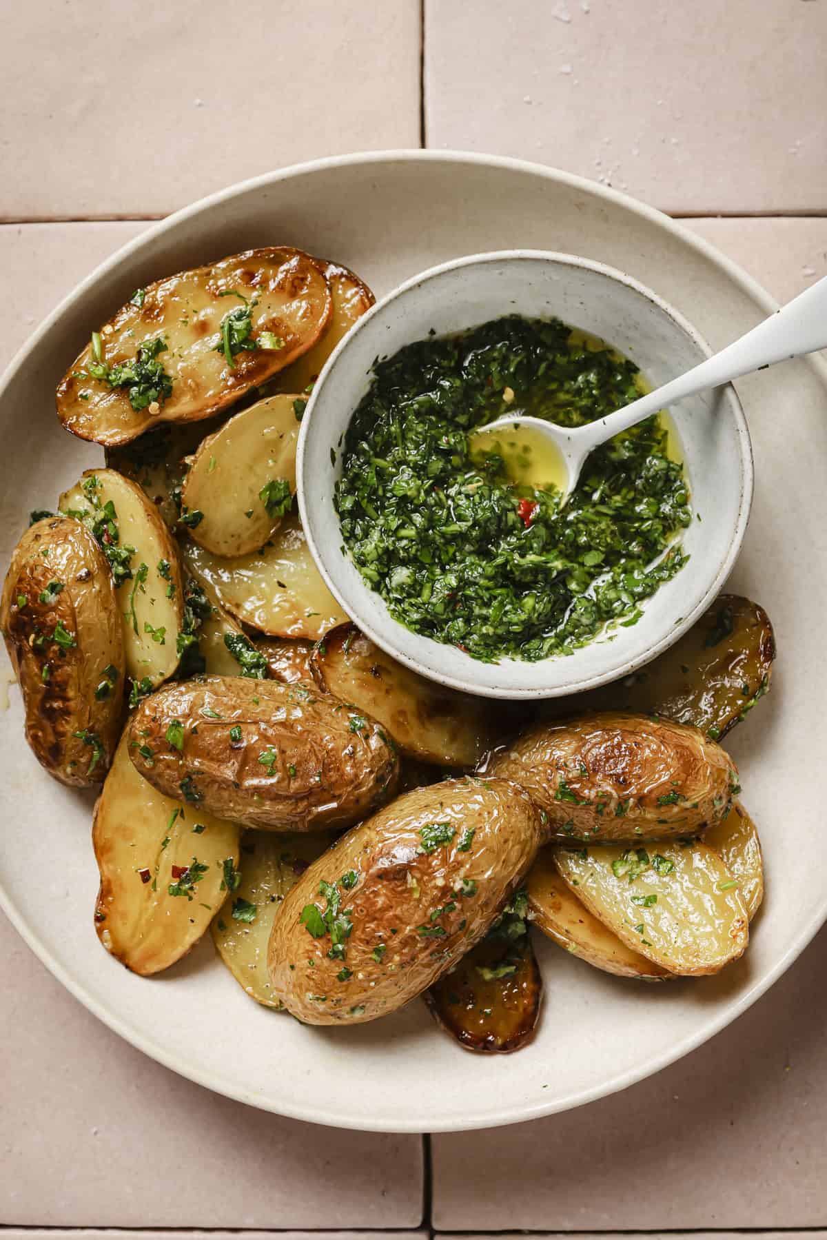 bowl with roasted potatoes covered in gremolata and a small bowl of herb oil gremolata.