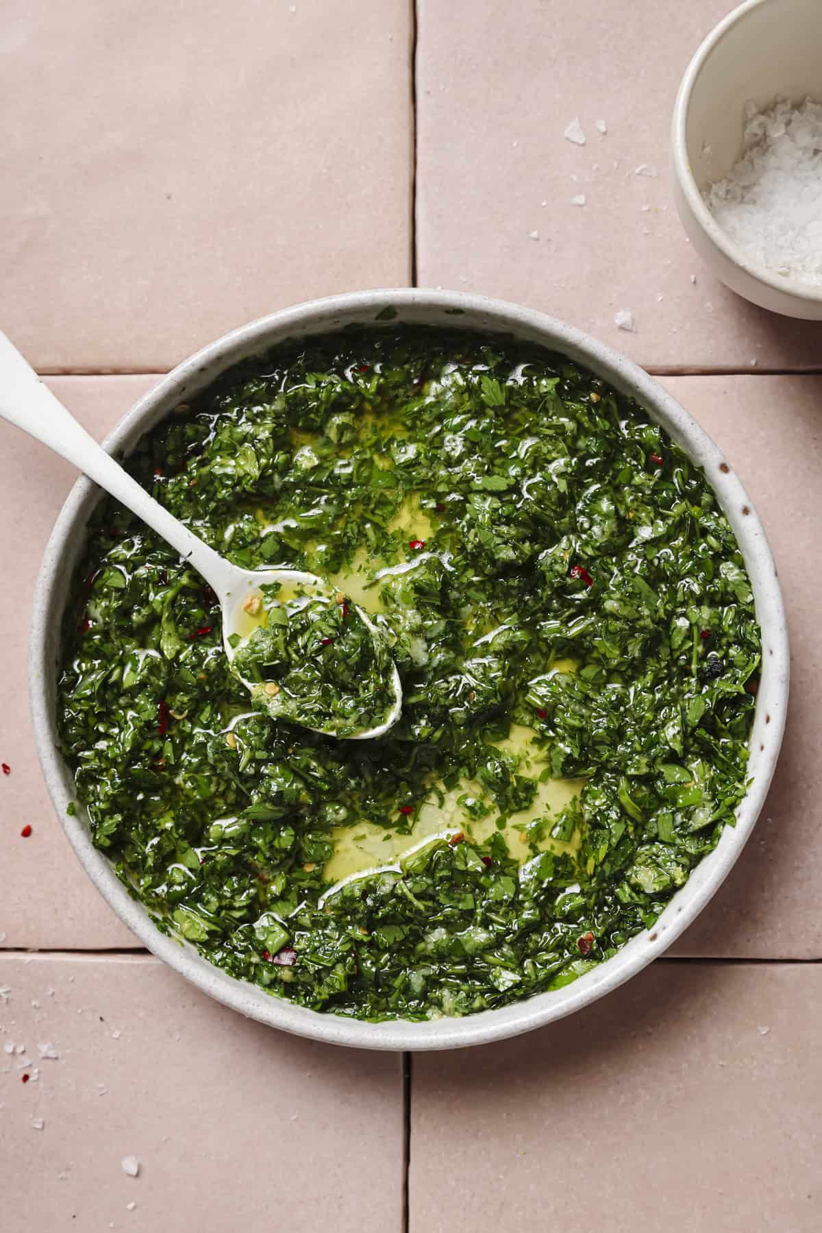 overhead photo of herby oil gremolata in a bowl with a spoon.