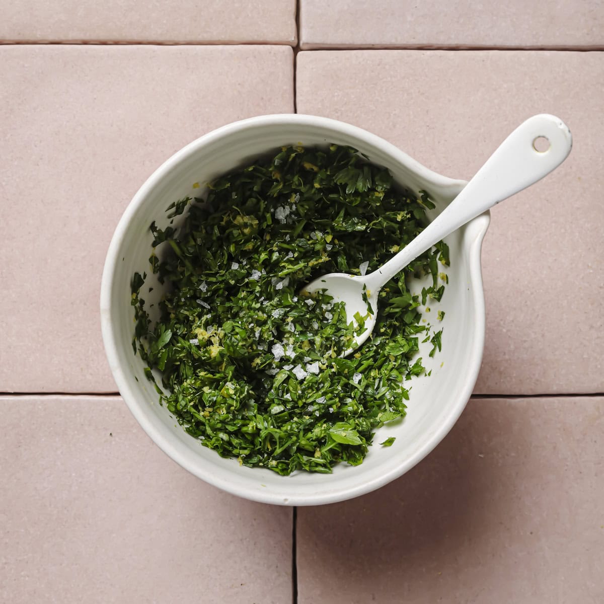 mixed gremolata with sea salt in bowl with a spoon.