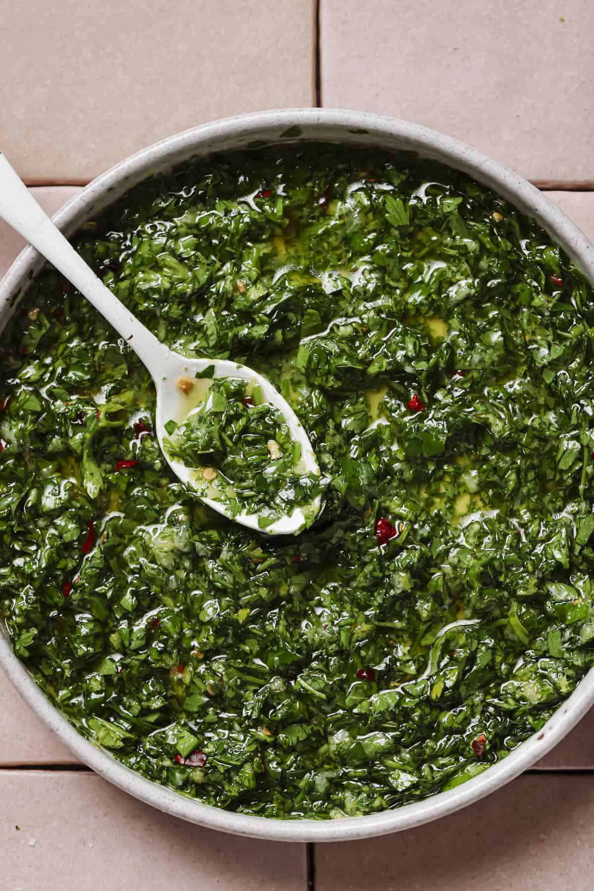 close up overhead shot of gremolata herb oil in a bowl with a spoon.