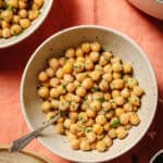 overhead view of cooked chickpeas with parsley in a bowl with a silver spoon in it.
