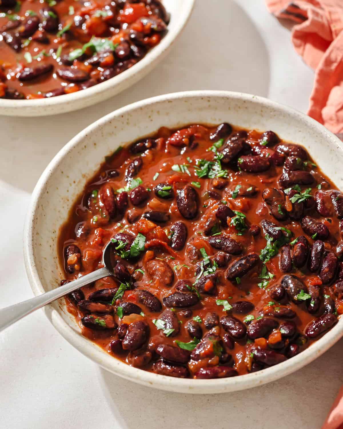 saucy cooked kidney beans in a bowl with a silver spoon.