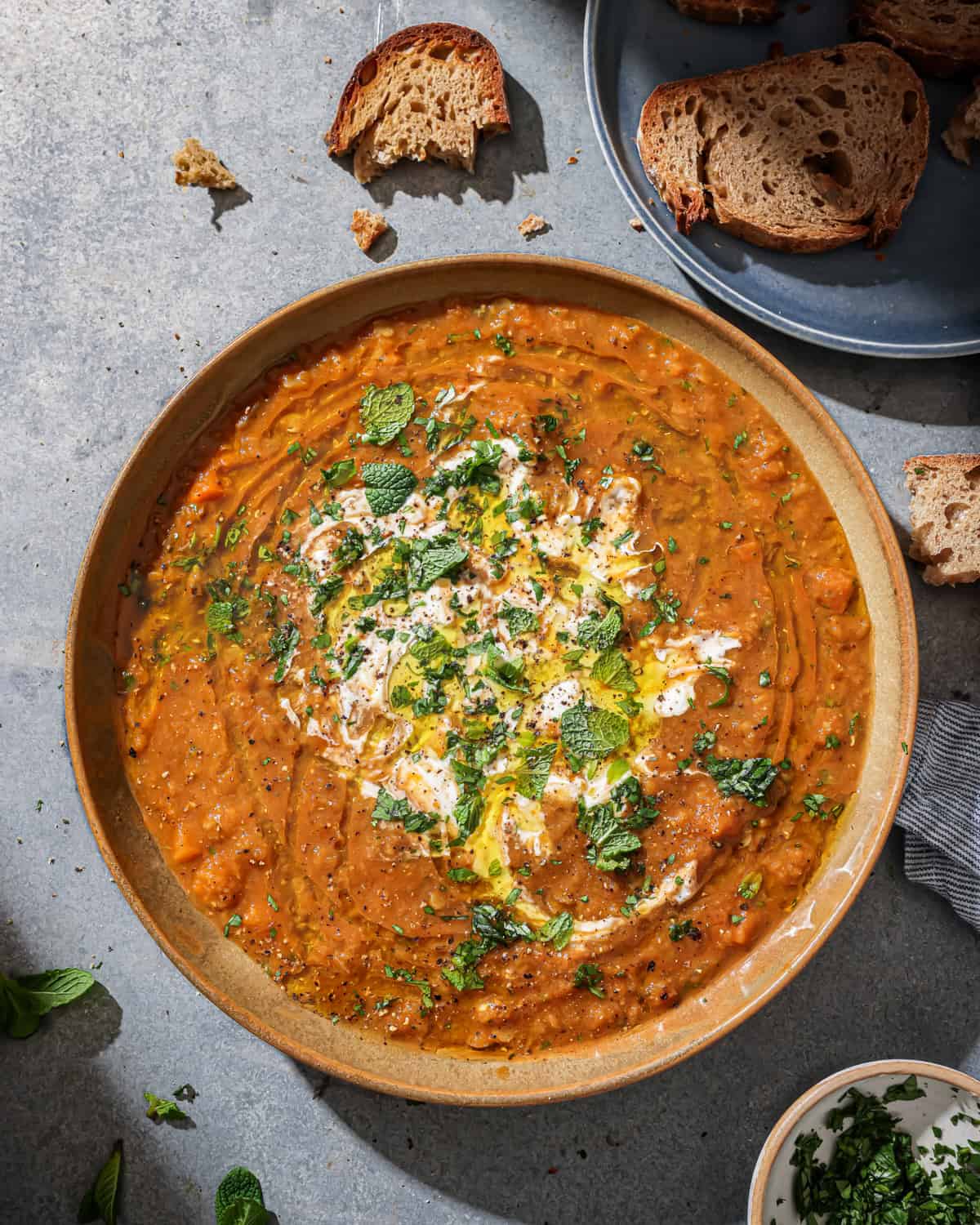 Overhead photo of a bowl of soup topped with coconut yogurt and fresh herbs.