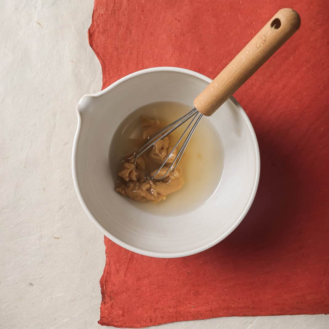 miso and rice vinegar in a bowl with a whisk.