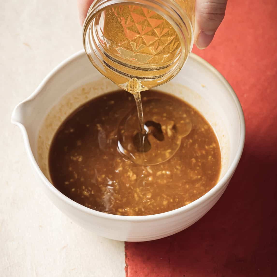 person streaming sunflower oil into the bowl.