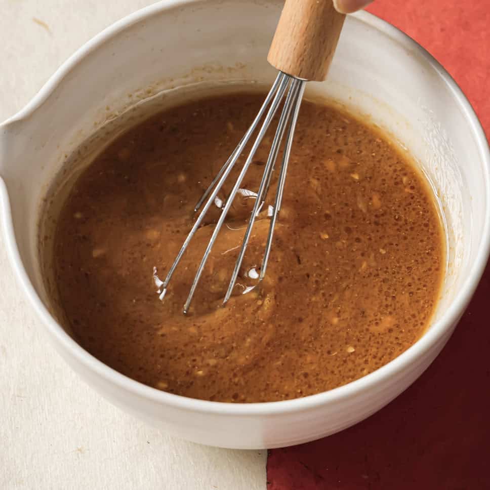person whisking finished sesame miso dressing in the bowl.