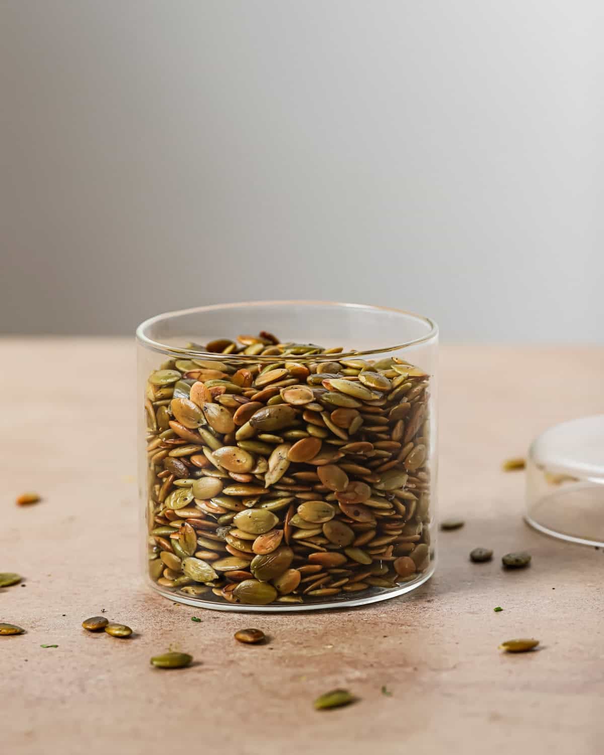 glass jar filled with roasted pepitas on a table.