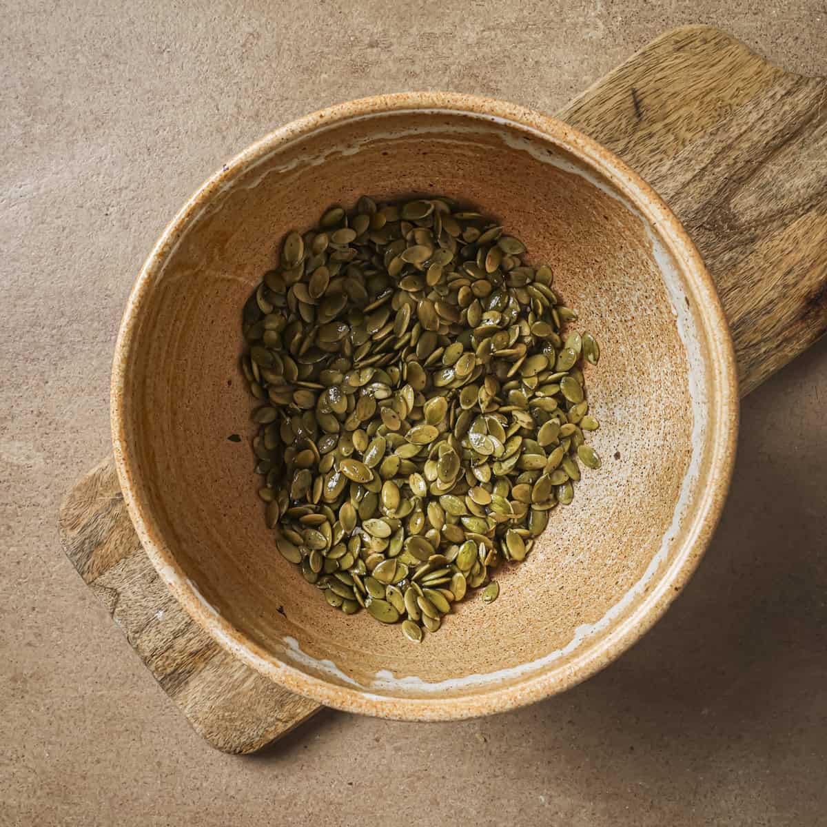pepitas with oil, salt and pepper in a bowl on a table.