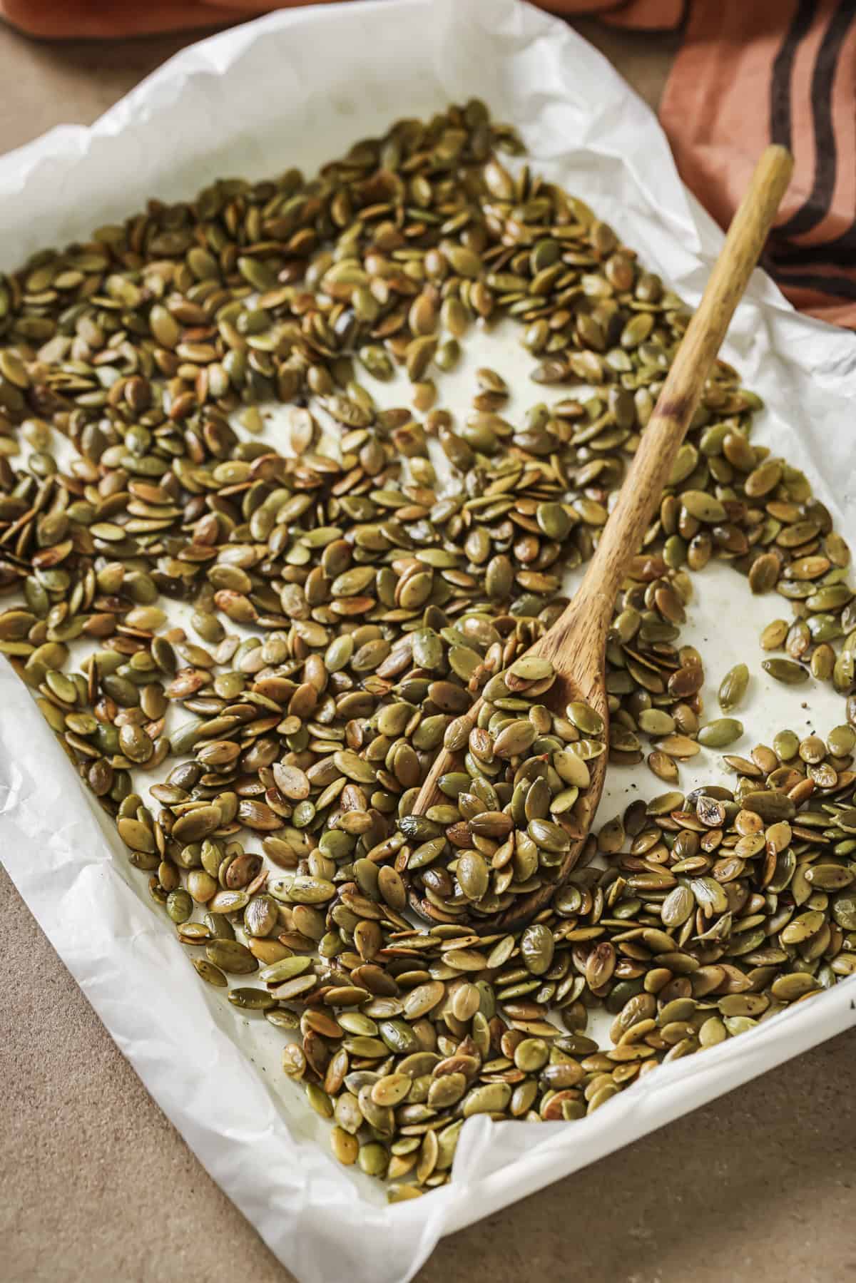 roasted pepitas on a parchment paper lined sheet pan.