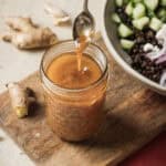 Person removing a spoon from a jar of sesame miso dressing.