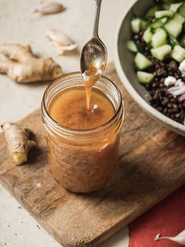 Person removing a spoon from a jar of sesame miso dressing.