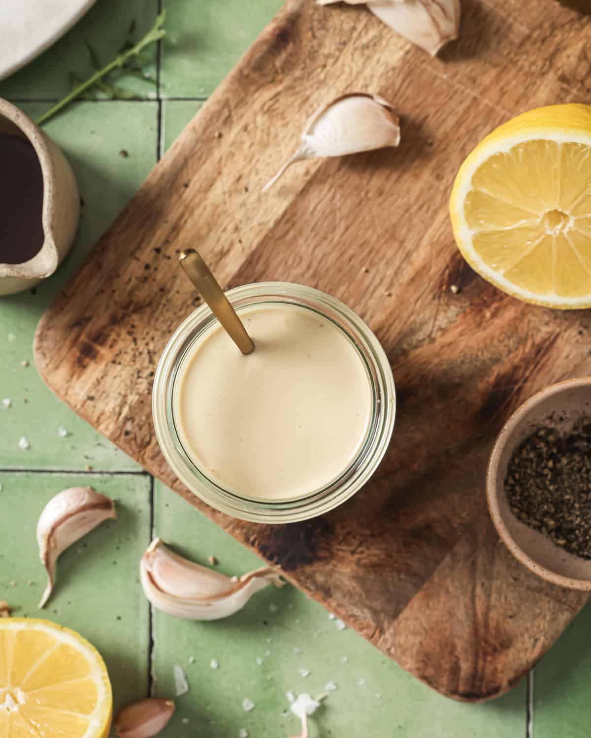 overhead view of jar of tahini dressing on a wooden cutting board.