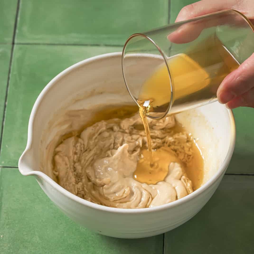 person pouring olive oil into bowl.