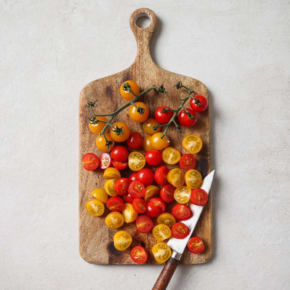 cherry tomatoes and a knife on a cutting board.