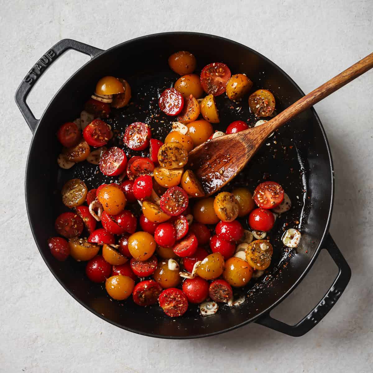 oil mixed in with the tomatoes in the pan.