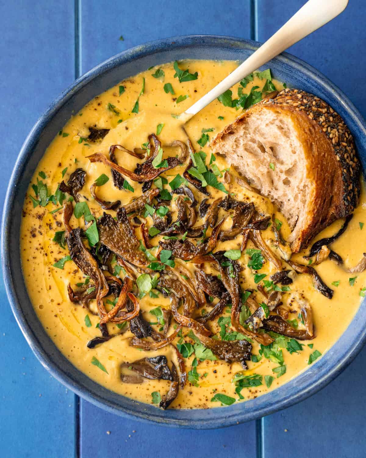 roasted mushrooms on a bowl of soup with a hunk of crusty bread.