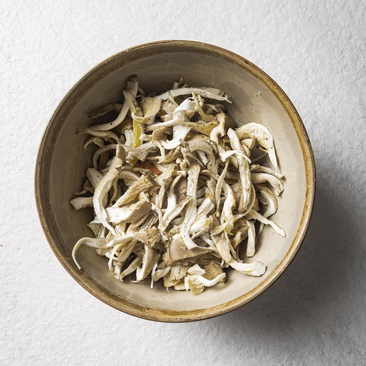 torn mushrooms with oil, salt and pepper in a bowl.