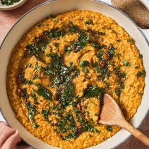 finished dal tadka in a deep saucepan with a wooden spoon.