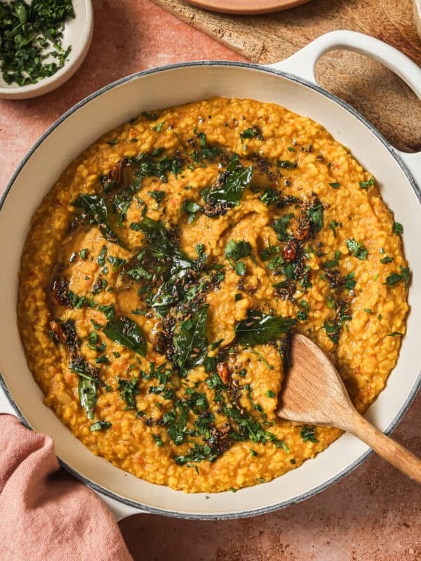 finished dal tadka in a deep saucepan with a wooden spoon.