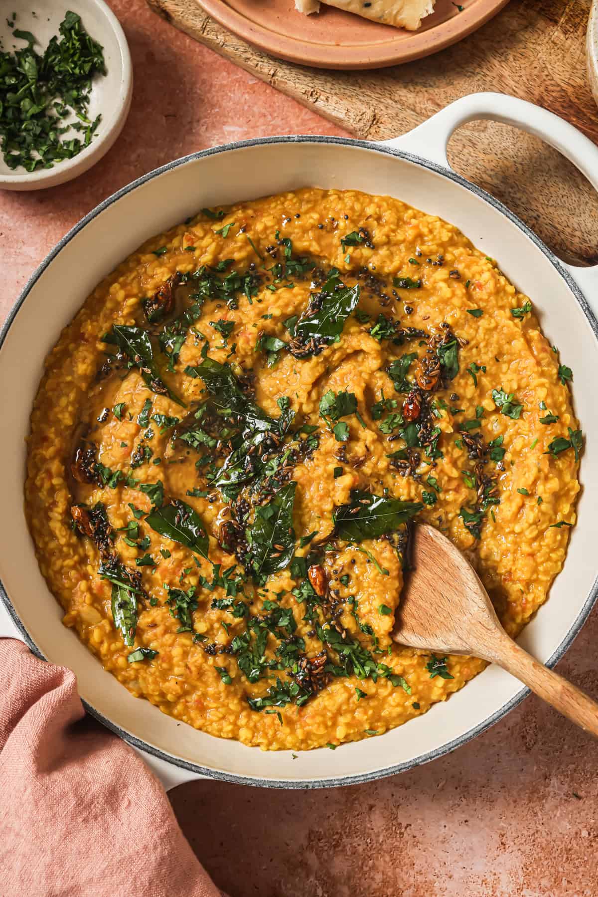 finished dal tadka in a deep saucepan with a wooden spoon.