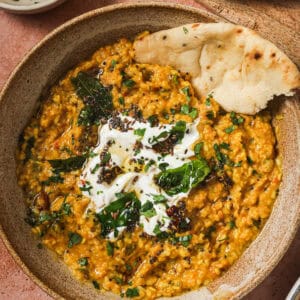 overhead view of bowl of dal tadka with yogurt and a piece of naan.