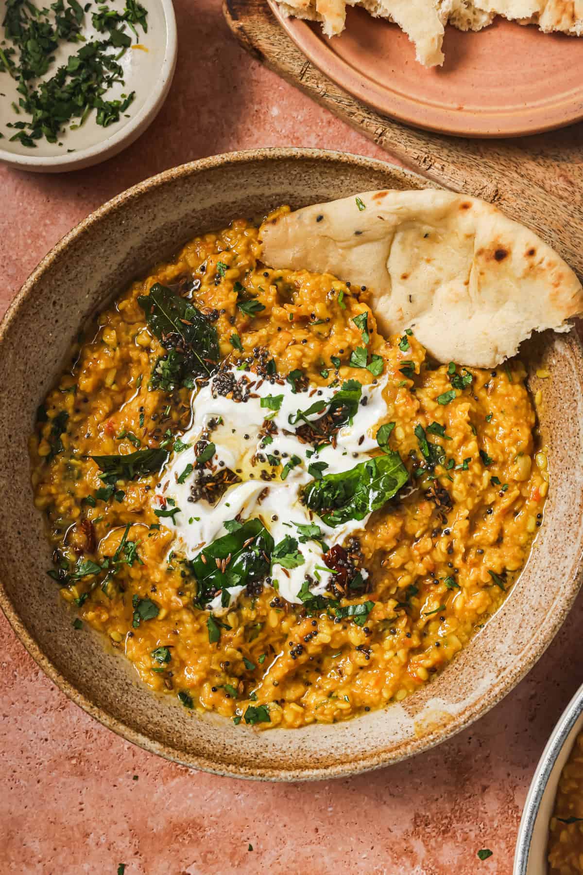 overhead view of bowl of dal tadka with yogurt and a piece of naan.