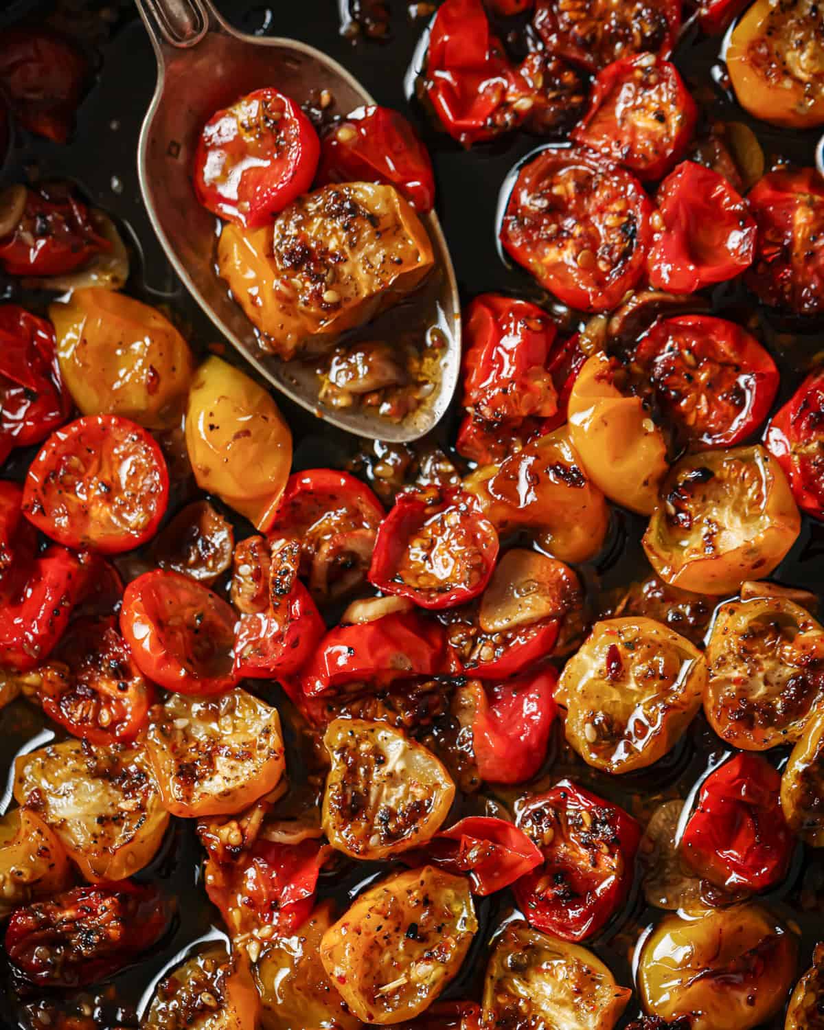 person holding up spoonful of confited tomatoes over the pan.