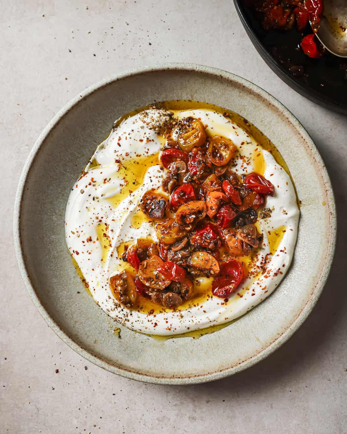 bowl of vegan yogurt with spices and confited tomatoes with their oil.