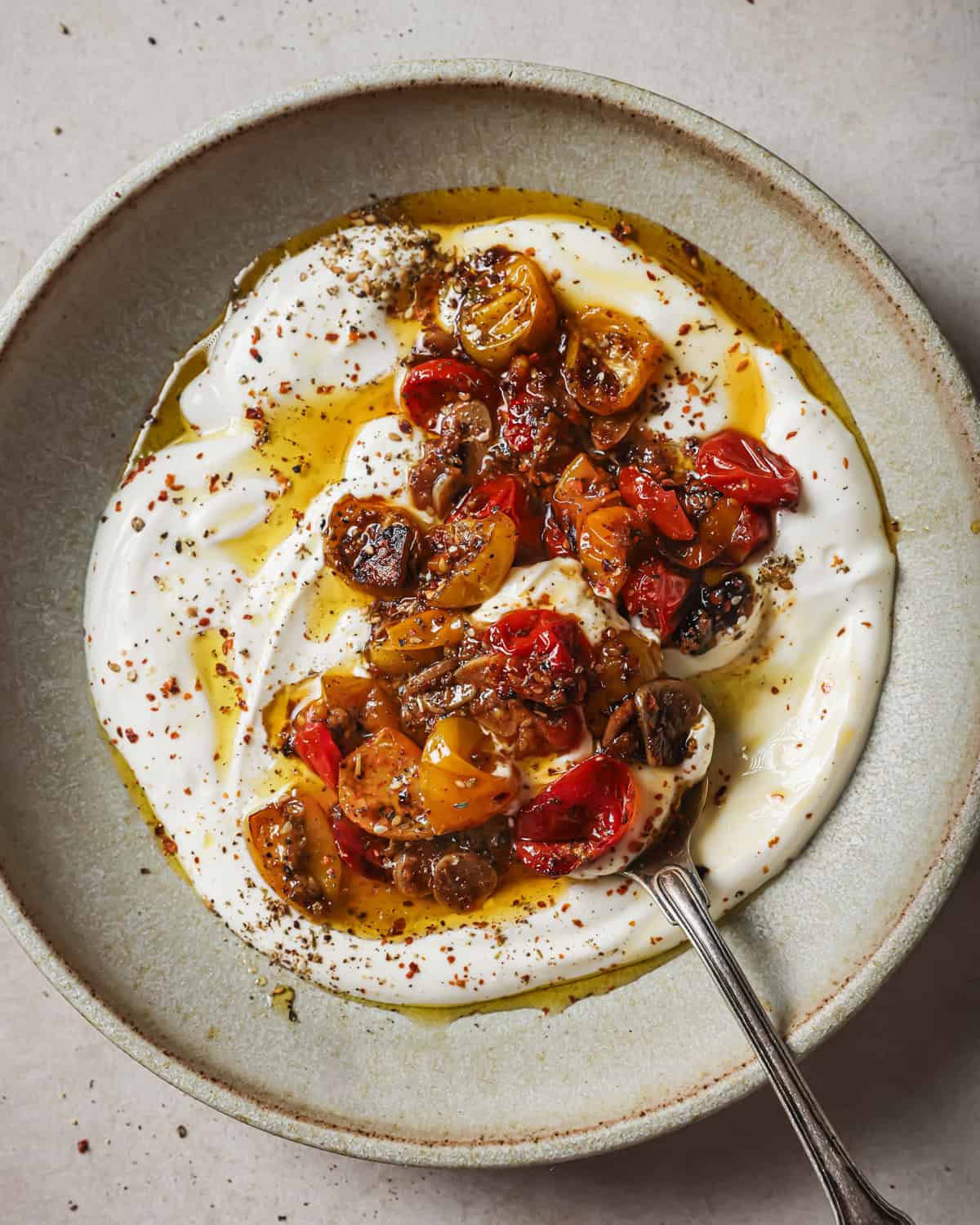 vegan yogurt, spices and confited tomatoes with their oil in a bowl.