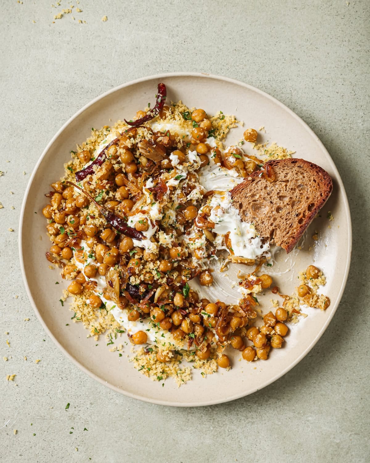 fried chickpeas with yogurt sauce with a piece of bread on a plate.