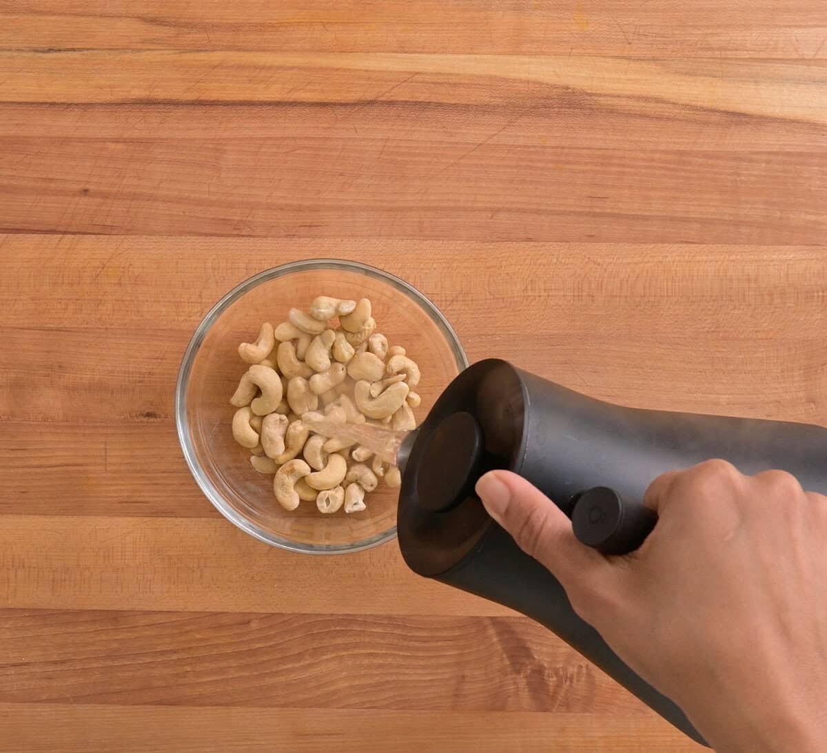 person pouring boiling water over cashews in a bowl.