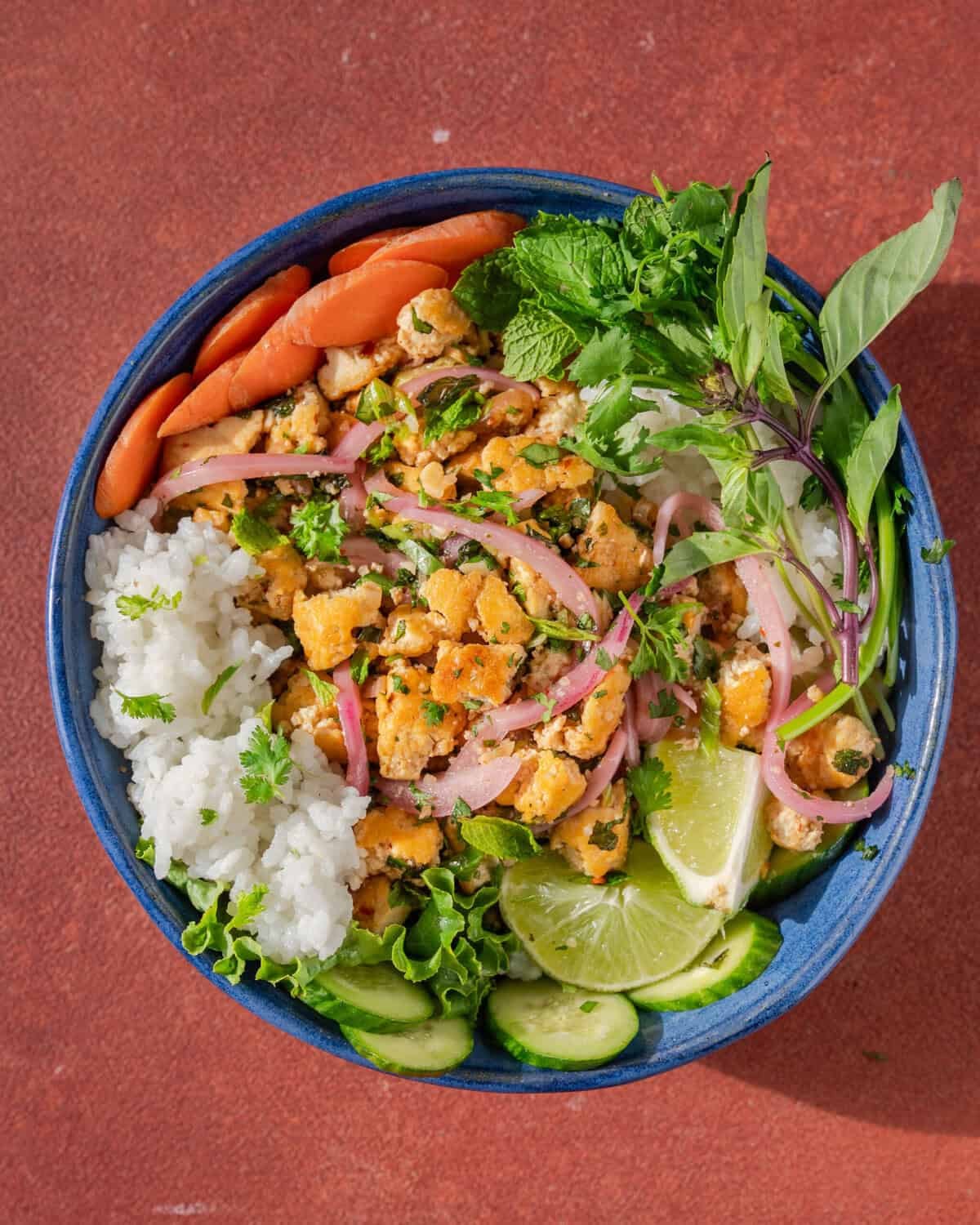 thai laab rice bowl with fresh veggies, lime and herbs.