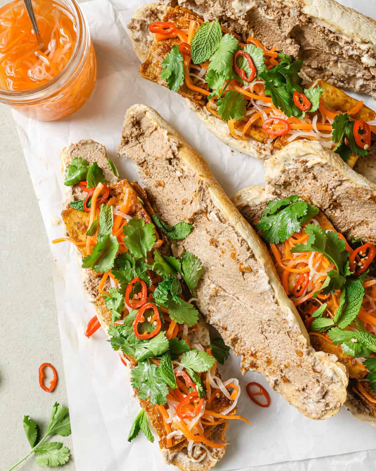 several open-faced vegan banh mi sandwiches on parchment paper.