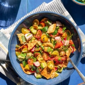 bowl of fattoush on a cloth napkin on a table.