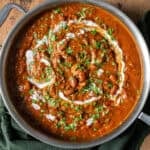 rajma masala topped with cilantro, tadka and yogurt in a deep saucepan on a table.