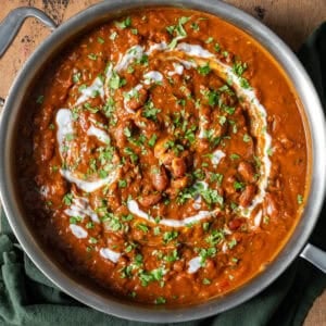 rajma masala topped with cilantro, tadka and yogurt in a deep saucepan on a table.