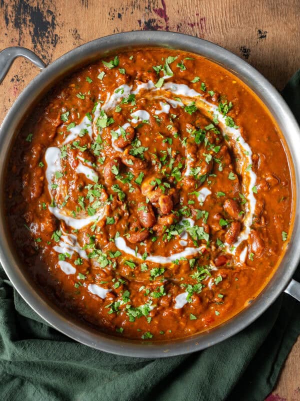 rajma masala topped with cilantro, tadka and yogurt in a deep saucepan on a table.