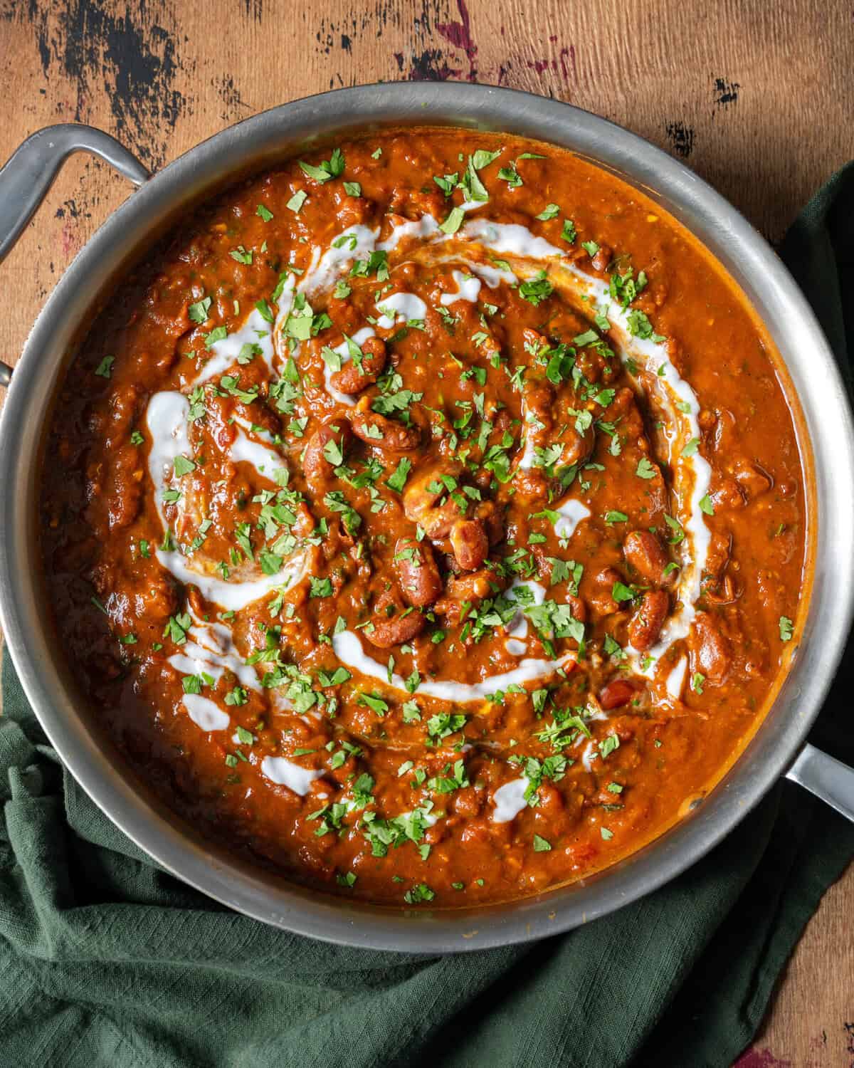 rajma masala topped with cilantro, tadka and yogurt in a deep saucepan on a table.